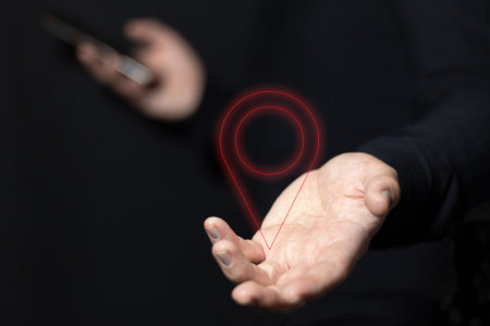 A man holding the location pin icon symbol while using his smartphone. GPS navigation marker sign. Search for routes with technology.の写真素材