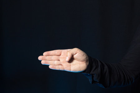 A man pointing with four fingers isolated on a dark background. Image with copy space.の写真素材