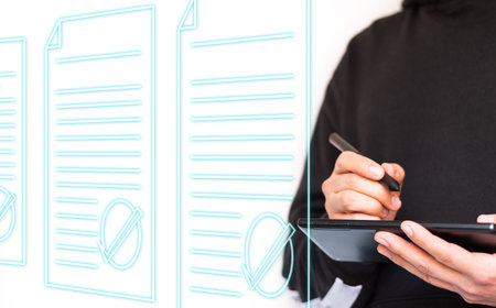 Unrecognizable young man in a hoodie using a tablet and digital pen to review documents. Holographic...