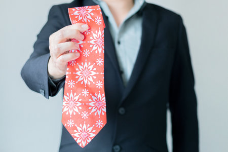 Elegant man in suit, showing to camera a red tie with Christmas design. End of year business party....