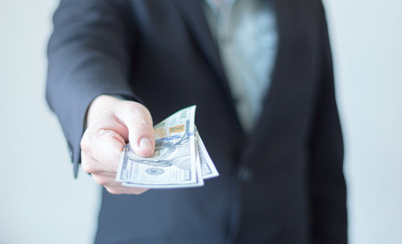 An unrecognizable businessman gives the camera one hundred dollar bills. payment, loan. Cash money...