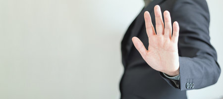 Web Banner of a businessman with hand in stop sign on a plain background. Rejection and warning, Unrecognizable elegant man in profile showing his open hand. Five fingers.の写真素材