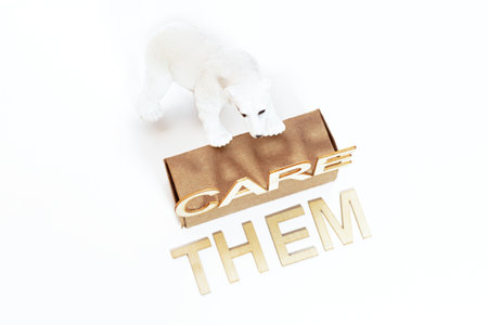 A toy polar bear standing on a box next to a wooden "save them" sign isolated on a white background. Concept of animal protection and environmental care.の写真素材