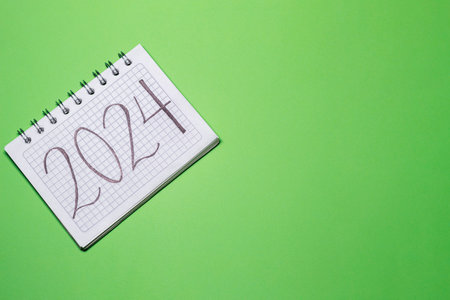 2024 Handwritten in a Notebook on a green background, image with Copy Space. Concept of the beginning of the year.の写真素材