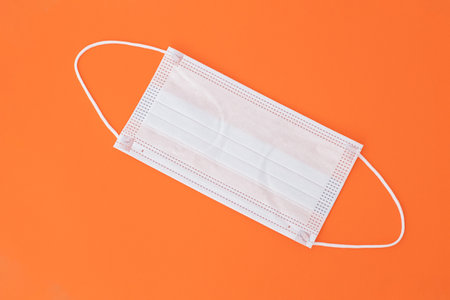 Medical Face mask on a flat orange background. Concept of health and disease.