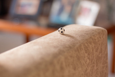 Tiny soccer ball on the back of a sofa with a blurred family settingの写真素材