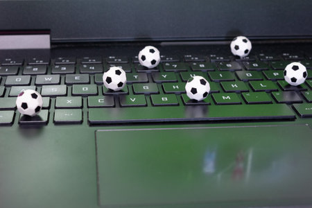 Mini soccer balls on a laptop keyboard reflecting a soccer game