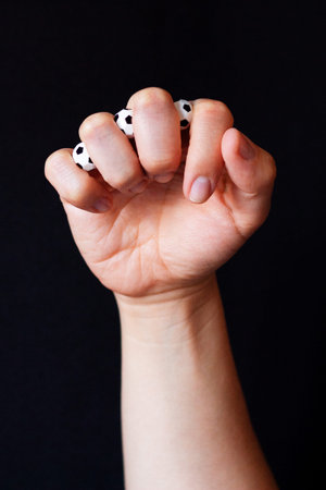 Clenched fist with small soccer balls visible between knuckles, metaphor for emotional tension and...
