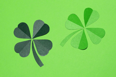 Minimalist composition of green four-leaf clovers on a monochromatic background. Traditional Irish...