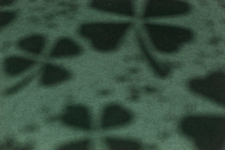 Shamrock shadows projected onto green surface. Conceptual St. Patrick's Day background. Seamless...