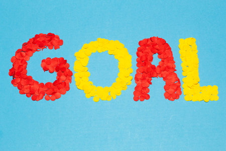 Text âgoalâ formed with red and yellow confetti on a blue background with a wide horizontal composition, concept of celebrating a soccer goalの写真素材