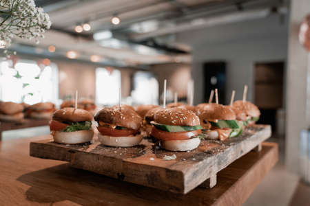 Tasty Burgers on a wooden board, beautifully prepared and well arranged. Finger food style. Dinner party invitation for lunch and lifestyle catering event served with bokeh and feeling hungry gourmet.の写真素材