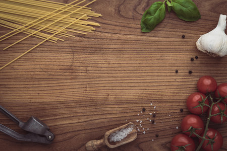 A frame, border, background composition made of pasta, tomatoes, basil, garlic and salt and pepper. Fresh healthy ingredients layed out as a nice border with space for text.の写真素材