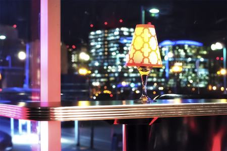A light fixture sitting on a table at a high end club. With the nigh time Boston urban skyline in...