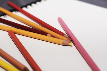 An arrangement of warm colored pencils on a paper white backgroundの写真素材