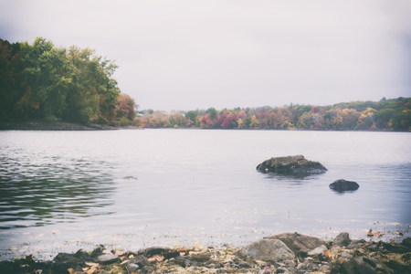A retro film style photo of a New England lake and forest in the fall.の写真素材