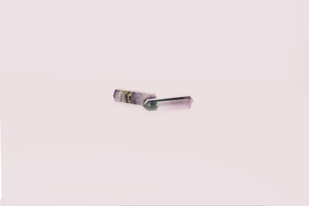 Two pieces of fluorite touching at the tips on a white background.