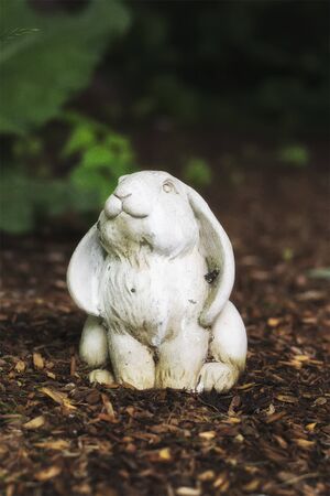 A granite lawn ornament of a rabbit out in a garden.の写真素材