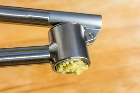 clove of garlic being crushed in garlic presの写真素材