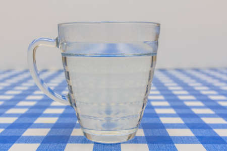 Tea glass of water standing on table with blue and white clothの写真素材