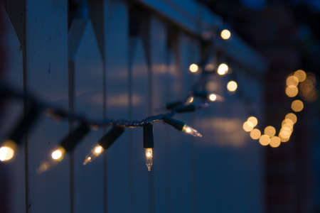 christmas lights in subdued light draped over residential fence
