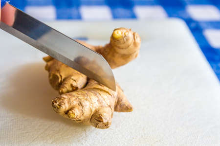 fresh ginger being sliced by a sharp knifeの写真素材