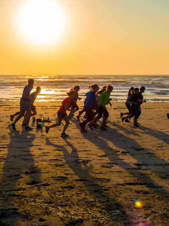 Kijkduin, The Hague, the Netherlands - May 14 2018: group of men and women running on the beach at sunsetのeditorial素材