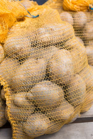 bags of rustic raw potatoes food in sacks on wood backgroundの写真素材