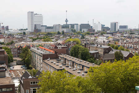 Rotterdam, the Netherlands - July 19 2019: mixed classic architecture of Rotterdam leafy urban apartment buildings in foreground with modern city high rise, tall towers and euro mast in backgroundのeditorial素材
