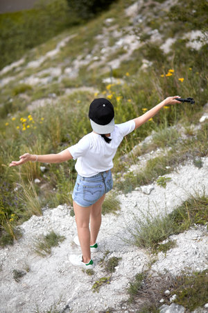 Girl in denim shorts with open arms standing on a rock road. Top viewの写真素材