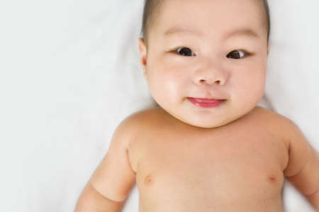 A cute little asian baby staring into the camera sticking out tongue の写真素材