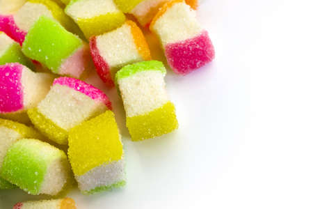 Top left corner pile up by colorful soft chewy sugar coated sweet candies on white. の写真素材