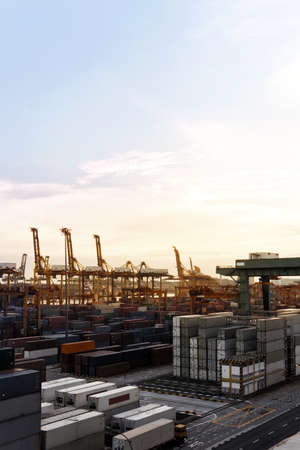 Vertical shot of a Harbor with lots of Cranes and cargo containers in a golden sunset view