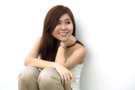 Beautiful Asian lady sitting looking away with white backgroundの写真素材