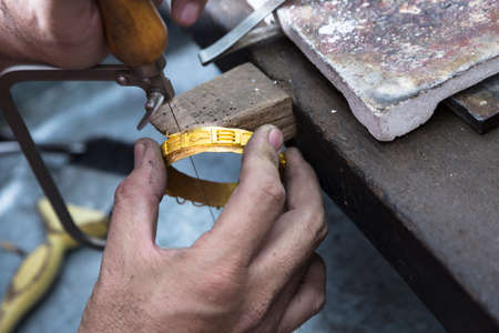 Close up of Jeweler crafting golden bangle with flame torch.の写真素材