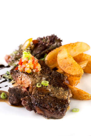 A vertical shot of a plate of thick juicy beef steak to be served with fries and salad on isolated white.の写真素材