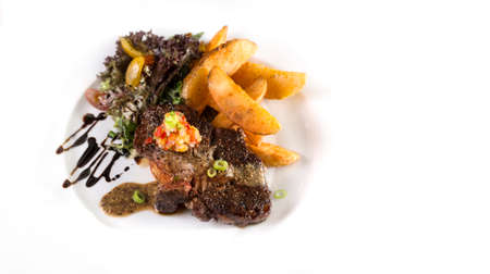 A  plate of thick juicy beef steak to be served with fries and salad on isolated white.の写真素材
