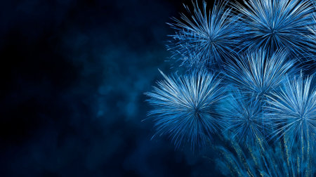 Spectacular blue and turquoise fireworks exploding with multiple starbursts trails and sparkling lights on dark navy blue night sky with copy space, festive celebration atmosphere.の素材