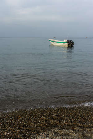 Motorboat in the sea seen from the coast with the sea and mountains in the distanceの写真素材