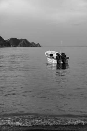 Small boat alone in the sea with the horizon and mountains in the distanceの写真素材