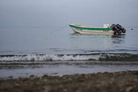Single boat with green line in the sea seen from the coast