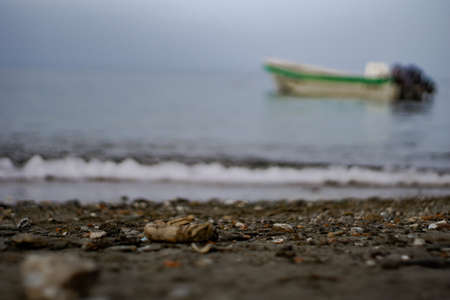 Single boat with green line in the sea seen from the unfocused coastの写真素材