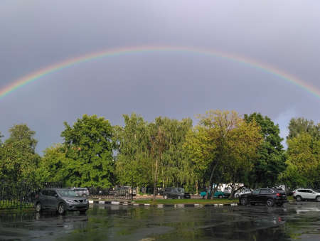 Puddles and total rainbow over the car parking. Moscow. Russiaの写真素材