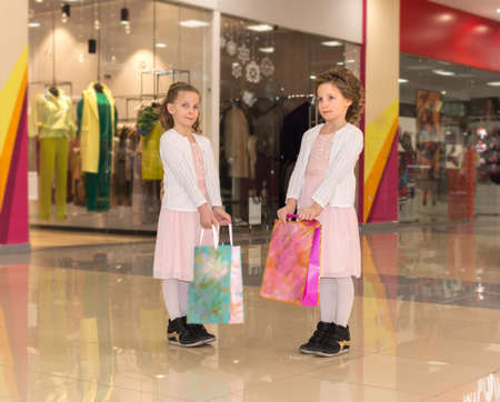 Two young twin sisters with shopping bags walking at the mallの写真素材