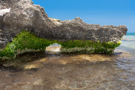 Rocky shore with a small grotto. Detail of the rocky coastline. Rhodes. Greece