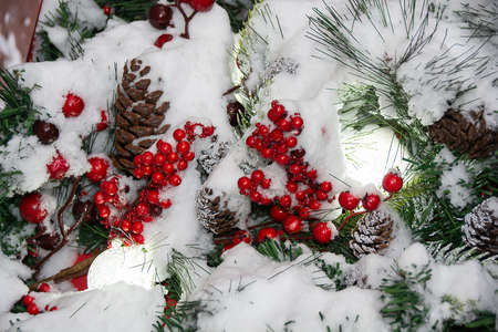 Christmas tree branches, red berries and lamps under snowの写真素材