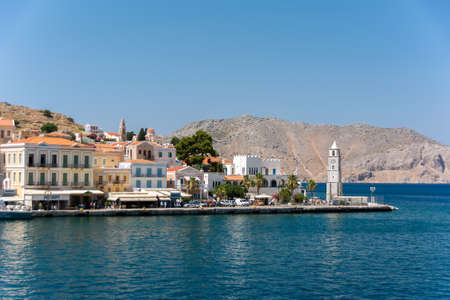 SYMI, GREECE - JUNE 25, 2019: Bay, clock tower, and old buildingsのeditorial素材