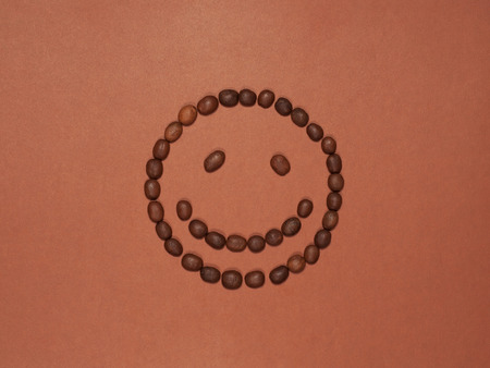 Smiling face made of coffee beans, isolated on brown backgroundの写真素材