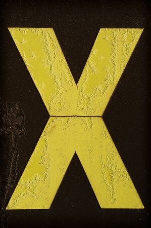 Yellow letter X covered with frost on black backgroundの写真素材