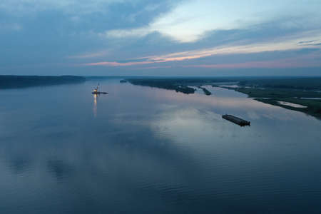 An aerial view of the barge on the river in the evening. View from a drone, sand mining, mining....